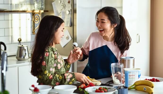 Woman and child laughing while preparing food