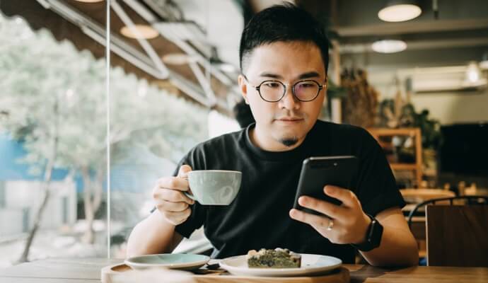 Man enjoying meal  looking at cell phone launching Norton 360 Standard.